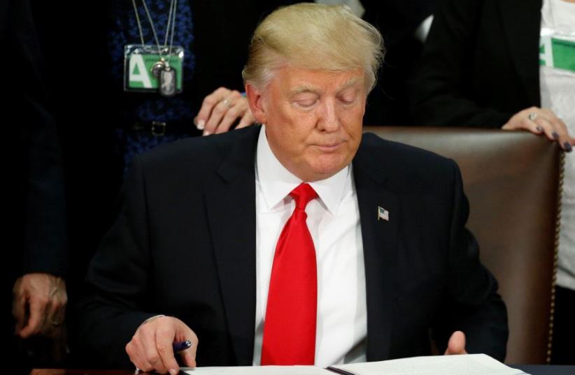 U.S. President Donald Trump reads an executive order before signing it at Homeland Security headquarters in Washington, U.S (photo credit: REUTERS)