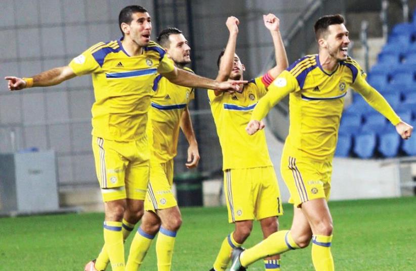 Maccabi Tel Aviv players celebrate last night in Netanya after clinching victory over Hapoel Ra’anana in a penalty shootout in the State Cup round of 16.  (photo credit: ADI AVISHAI)