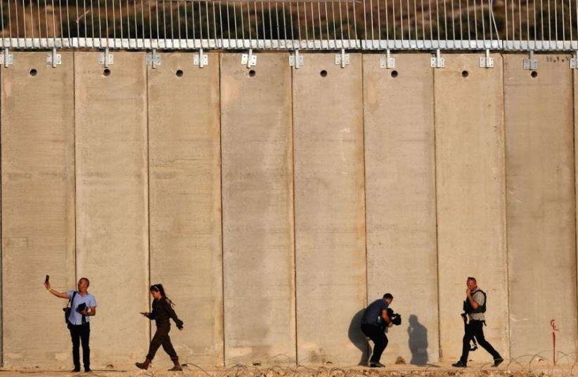 Security personnel walk in front of the barrier with the West Bank near Havat Ella, 20 km. southwest of Hebron. (photo credit: REUTERS)