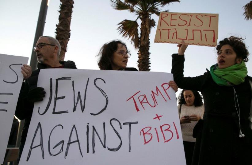 Protestors hold placards during a rally supporting refugees worldwide and in reaction to Trump's travel ban, outside the US embassy in Tel Aviv, Israel January 29, 2017 (photo credit: REUTERS)
