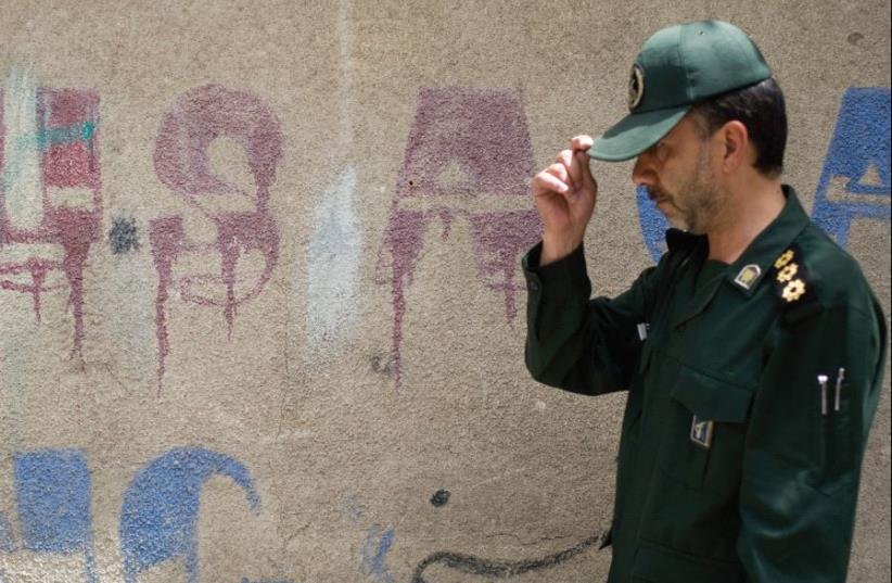 A MEMBER of Iran’s Revolutionary Guard walks past anti-US graffiti at a ceremony in 2008 to mark the anniversary of the death of Islamic Republic founder Ayatollah Ruhollah Khomeini. (photo credit: REUTERS)