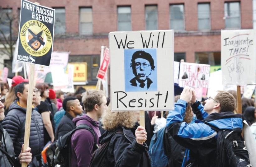 PROTESTERS HOLD up a sign urging people to ‘resist’ Donald Trump. But is some activism catering to the wrong extremes? (photo credit: REUTERS)