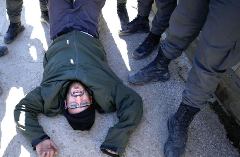 Policemen remove a pro-settlement activist during the second day of an operation to evict settlers from the illegal outpost of Amona in the West Bank, on February 2 (photo credit: REUTERS)