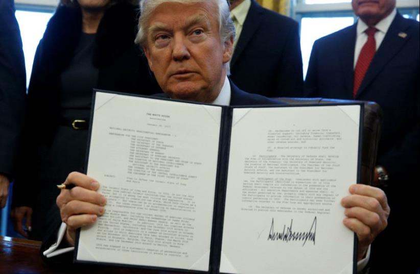 Donald Trump signs a memorandum to security services directing them to defeat the Islamic State in the Oval Office at the White House in Washington, US January 28, 2017.  (photo credit: REUTERS)