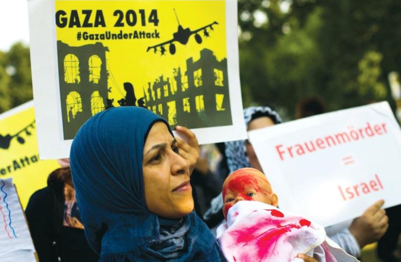 People hold placards during an anti-Israel protest in central Berlin in July 2014. The placard reads ‘Women murderers = Israel.’ (photo credit: REUTERS)
