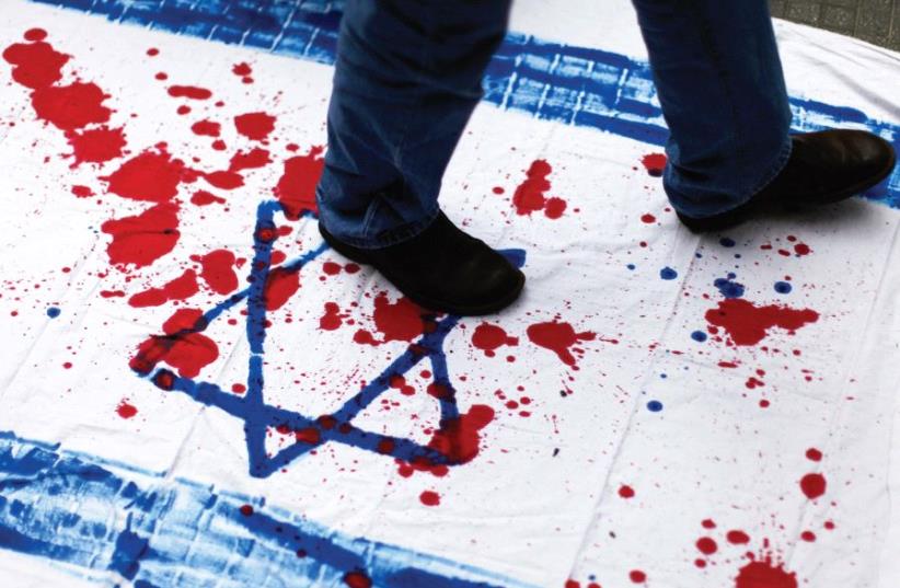 A VENEZUELAN student walks over a cloth with red paint and the Star of David during an anti-Israel demonstration. (photo credit: REUTERS)