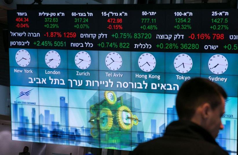 A man stands in front of an electronic board displaying market data at the Tel Aviv Stock Exchange (photo credit: REUTERS)