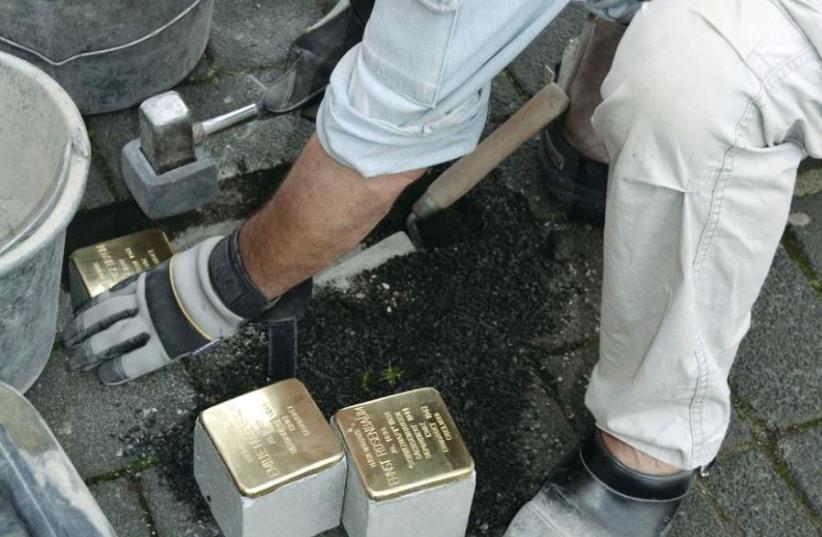 Artist Gunter Demnig lays Stolpersteine, small brass plaques that commemorate victims of the Nazis, in Cologne in 2015 (photo credit: KARIN RICHERT)