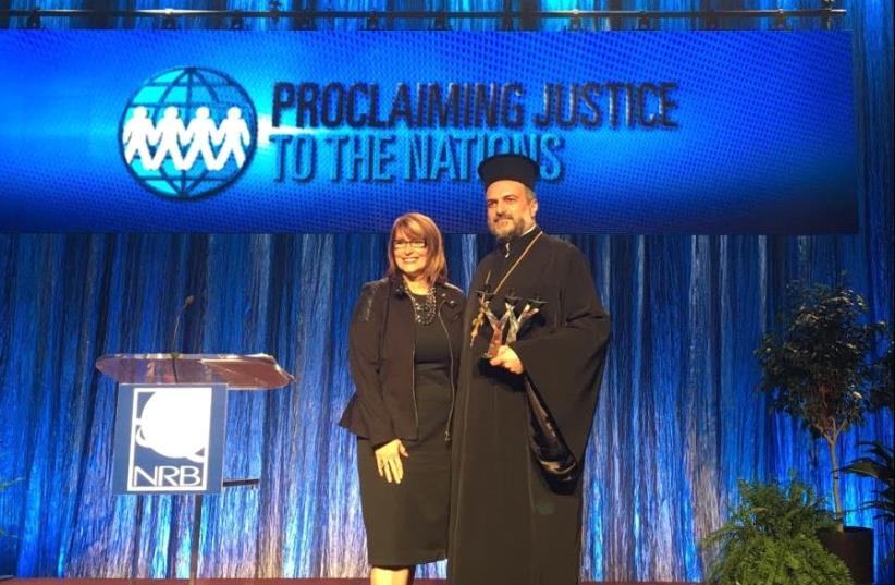 Laurie Cardoza-Moore, president of PJTN gives Father Naddaf the 'Ed McAteer Tree of Life Award' (photo credit: PJTN)