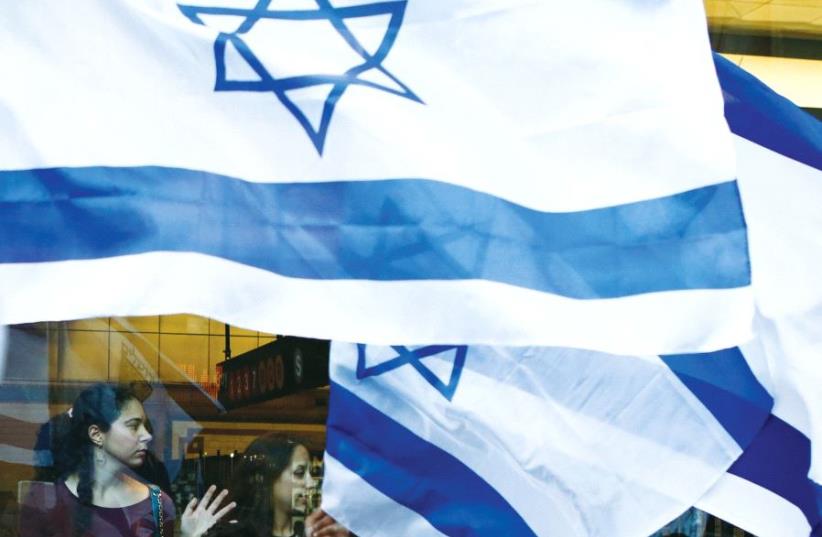 Women watch pro-Israel supporters wave Israeli flags and rally at Times Square in New York, to show support during Operation Protective Edge, summer 2014 (photo credit: REUTERS)