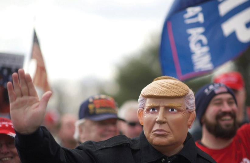 A marcher in a Trump mask.  (photo credit: REUTERS)