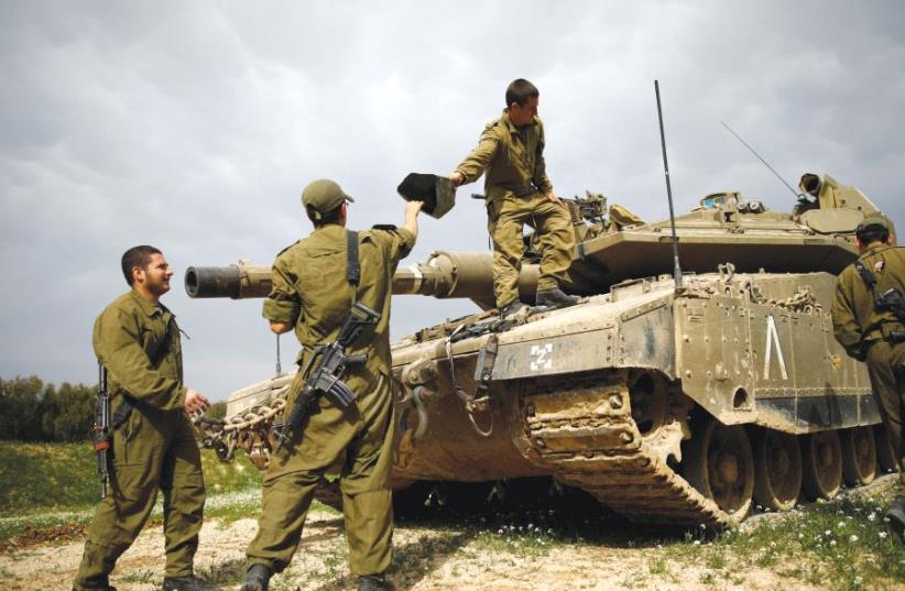 Soldiers are seen next to a tank, near the border with the central Gaza Strip last month (photo credit: REUTERS)