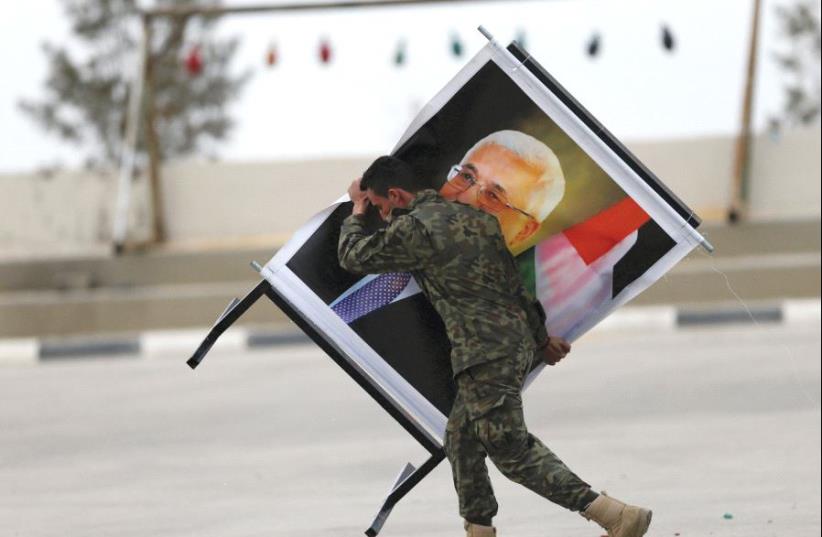 A soldier carrying an Abbas picture (photo credit: REUTERS)