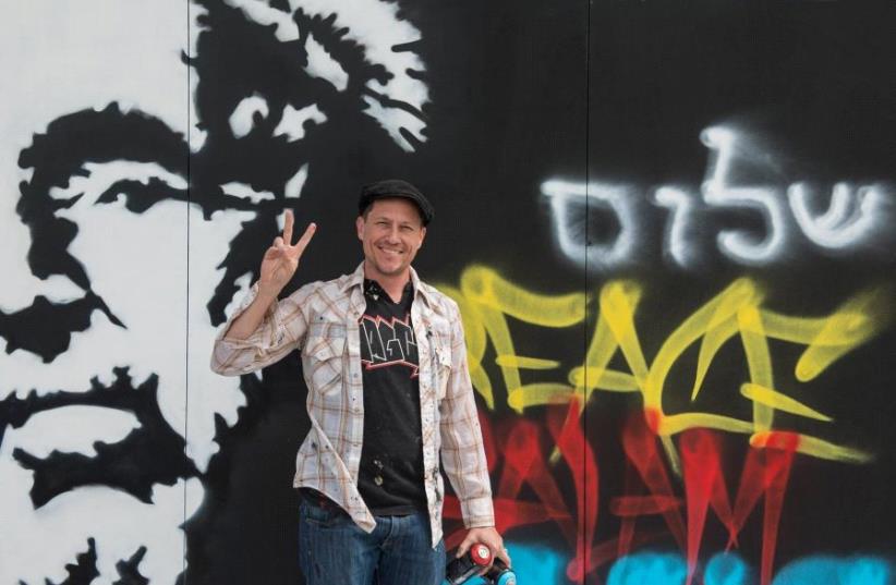 Graffiti artist and actor Corin Nemec stands by his creation at the Peres Center for Peace. (photo credit: BENNY DOUTSH)
