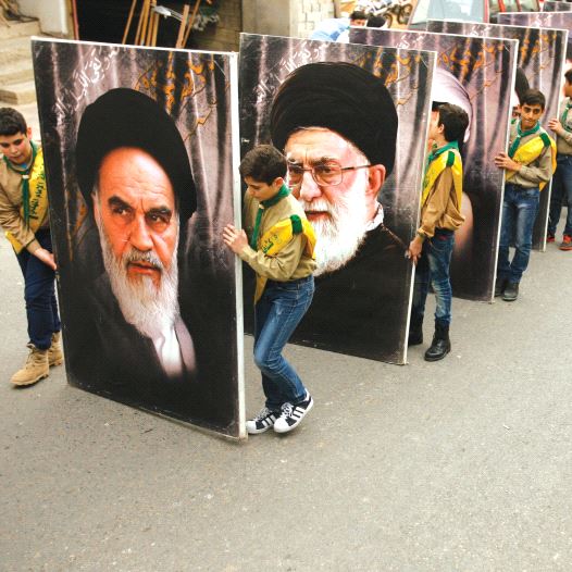 Hezbollah supporters carry portraits of the founder of Iran’s Islamic Republic, Ayatollah Ruhollah Khomeini (left), and supreme leader Ayatollah Ali Khamenei, as they march in the southern Lebanese town of Kfar Hatta / AFP PHOTO 