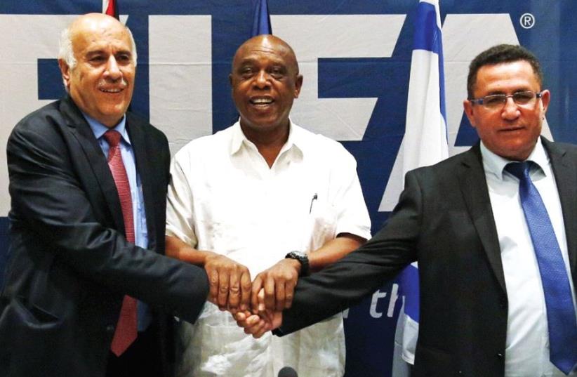 Jibril Rajoub (left), president of the Palestinian Football Association, Tokyo Sexwale (center), chairman of the FIFA Monitoring Committee Israel-Palestine and Israel Football Association president Ofer Eini shake hands following a news conference in Jericho in December 2015. (photo credit: REUTERS)