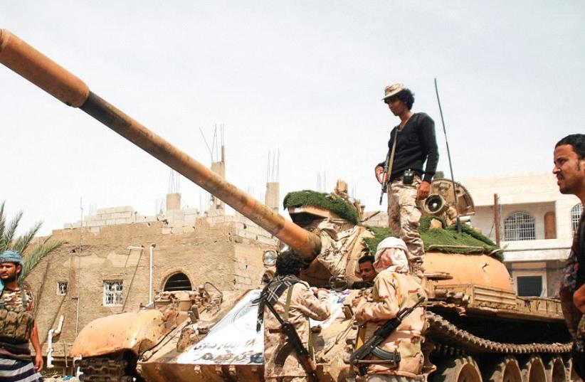 PRO-GOVERNMENT FIGHTERS gather next to a tank they use in the fighting against Houthi fighters in the southwestern city of Taiz in Yemen. (photo credit: REUTERS)