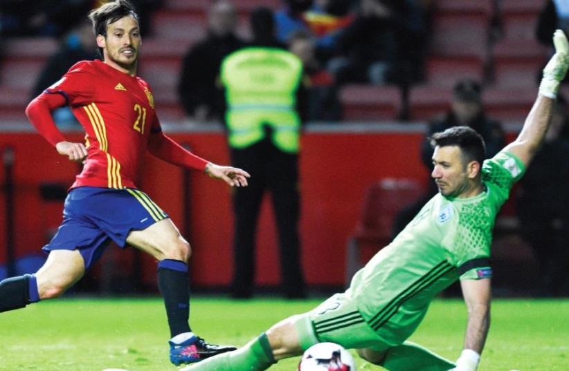 Spain midfielder David Silva (left) scores the opener in Friday’s 4-1 win over Israel in 2018 World Cup qualifying in Gijon with a low shot through the legs of blueand- white goalkeeper Ofir Marciano (photo credit: REUTERS)