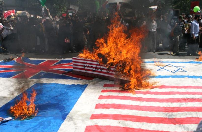 Iranian demonstrators burn the flags of Israel, the United States and Britain as they take part in the Jerusalem Day demonstration in Tehran [File] (photo credit: REUTERS)