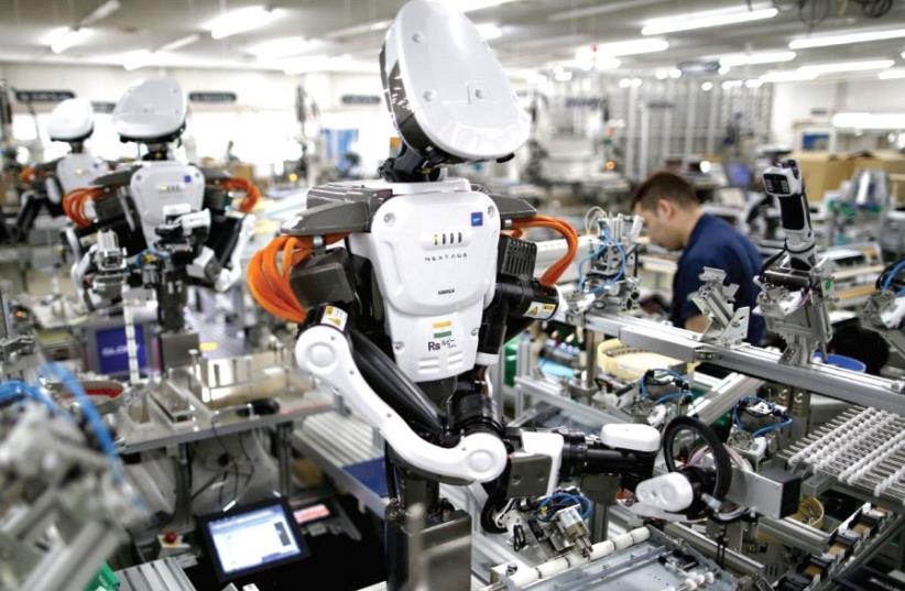 Humanoid robots work side by side with employees in the assembly line at a factory near Tokyo, Japan (photo credit: REUTERS)