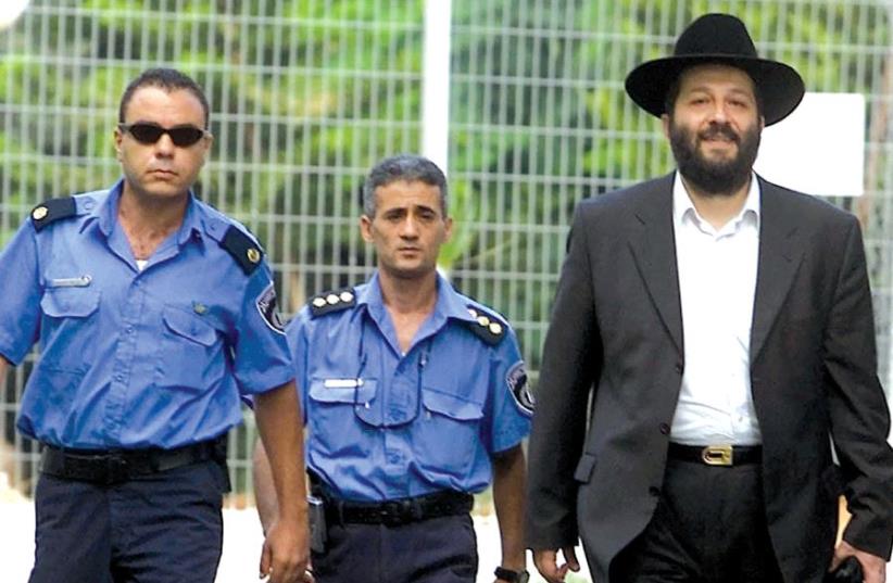 Aryeh Deri is escorted by policemen as he walks out of prison in 2002, after serving two years of a three-year sentence for corruption (photo credit: REUTERS)