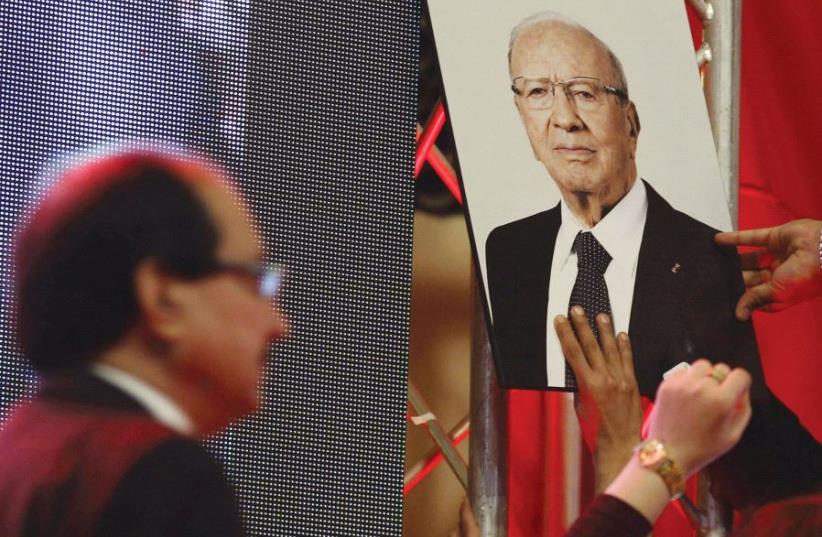 A man raises a picture of Tunisian President Beji Caid Essebsi, leader of the Nidaa Tounes party, January 2016 (photo credit: REUTERS)