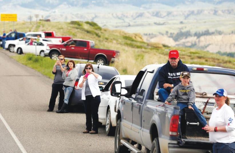 People watch along a highway in Billings, Montana, to catch a glimpse of then presidential candidate Donald Trump passing by on his way to a rally last year (photo credit: REUTERS)