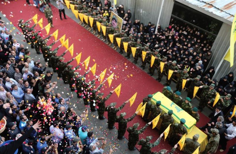 PEOPLE TOSS rose petals as Hezbollah members stand near the coffin of top Hezbollah commander Mustafa Badreddine, who was killed in an attack in Syria last year (photo credit: REUTERS)