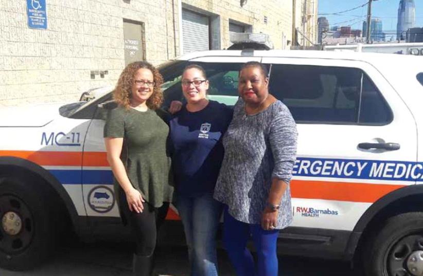 United Rescue volunteers, from left, Angela Ramos, Paula Hollenback and Shina Goodin, pose in front of an EMS vehicle at their facility in Jersey City, New Jersey earlier this month. (photo credit: NOA AMOUYAL)