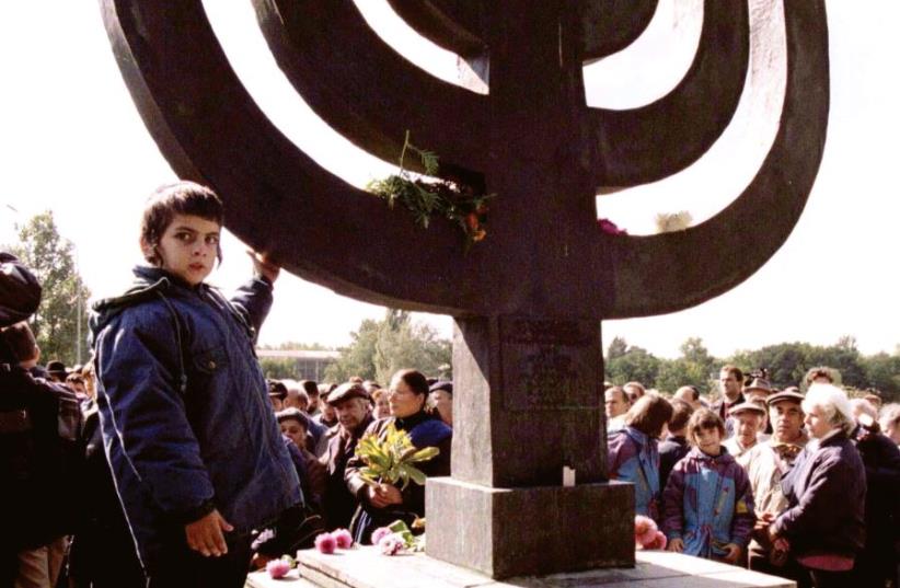 A Jewish boy stands by a memorial at Baby Yar in Kiev in 1996.  (photo credit: REUTERS)