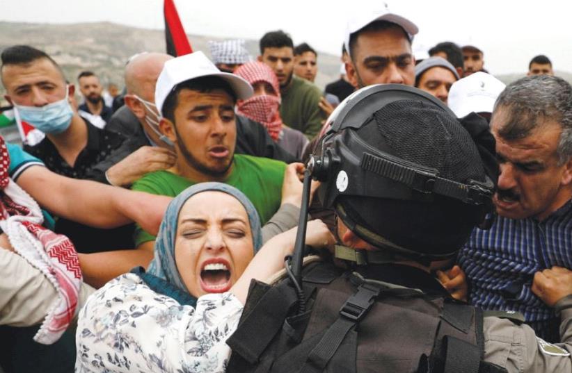 PALESTINIAN PROTESTERS clash with a soldier during a Land Day protest in Madama, south of Nablus. (photo credit: REUTERS)