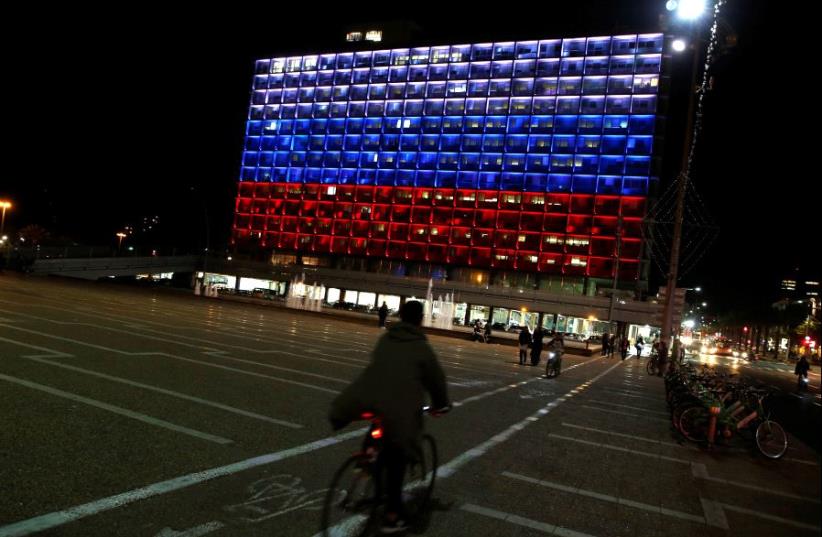 A man rides bicycle across the Tel Aviv city hall building as it is illuminated in solidarity with Russia after the blast in the St.Petersburg metro in Tel Aviv, Israel April 3, 2017 (photo credit: REUTERS)