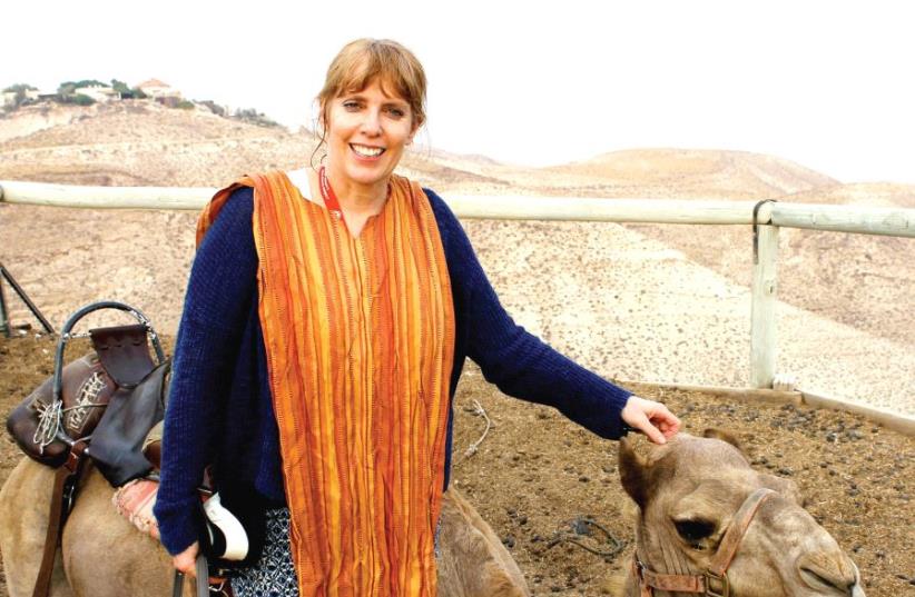 Author Shelly Sanders stands beside a camel at Genesis Land on the way to the Dead Sea during her trip with MOMENTUM (photo credit: Courtesy)