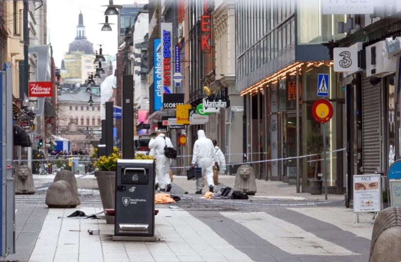Forensic specialists walk to the crime scene in central Stockholm April 8, 2017, the day after a hijacked beer truck plowed into pedestrians.  (photo credit: REUTERS/STRINGER)