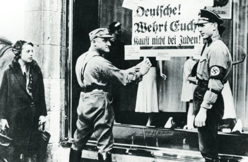 Nazi paramilitary officers stand outside a Berlin store in 1933 posting signs reading ‘Germans! Defend yourselves! Do not buy from Jews!’ (photo credit: GERMAN FEDERAL ARCHIVES)