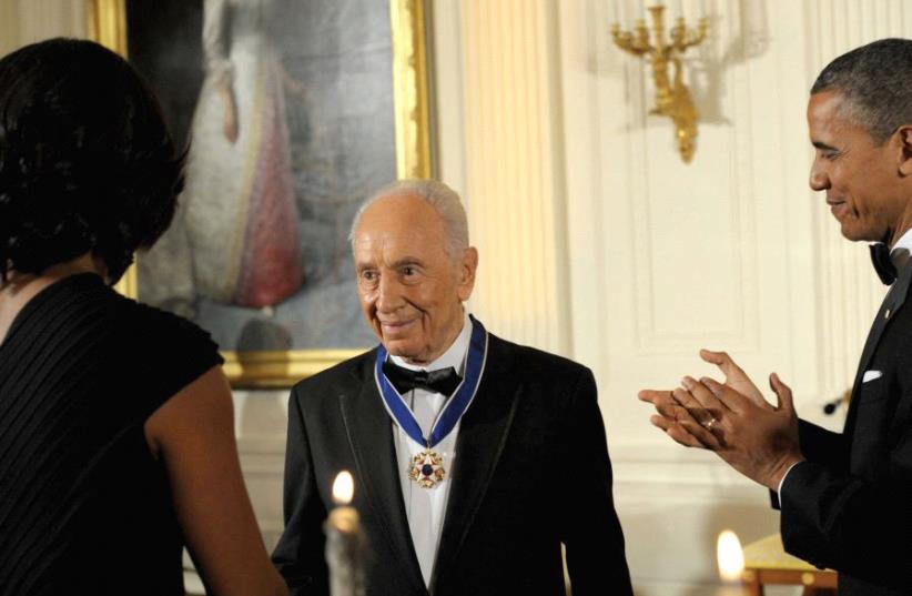 PRESIDENT BARACK OBAMA and first lady Michelle Obama applaud after awarding Peres the Presidential Medal of Freedom at the White House in 2012. (photo credit: GPO)