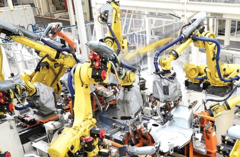 WELDING ROBOTS surround the body of a VW Golf car in a production line at the plant of German carmaker Volkswagen in Wolfsburg, Germany earlier this year. (photo credit: REUTERS)
