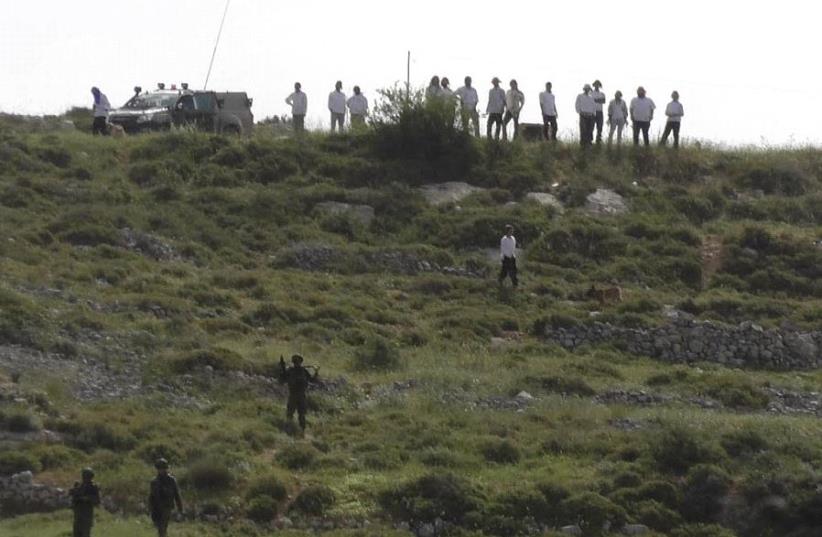Settlers and IDF soldiers stand on a hilltop outside the Yitzhar settlement (photo credit: YESH DIN)