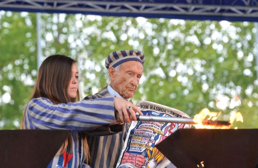 Survivor Edward Mosberg lights a memorial torch with his granddaughter on the 2016 March of the Living (photo credit: YOSSI ZELIGER)