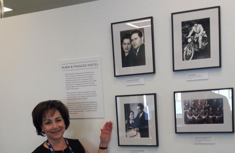 HARRIET SCHLEIFER, AJC Board of Governors Chair, proudly poses at the organization's new AJC office beside pictures of her parents who were Holocaust survivors from Poland (photo credit: NOA AMOUYAL)