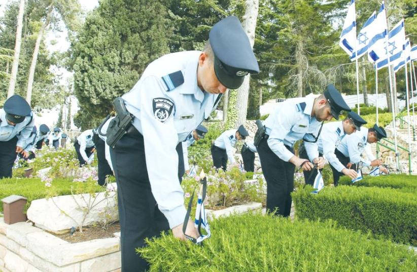 POLICE OFFICERS place flags on the graves of slain comrades at Mount Herzl in the capital yesterday (photo credit: MARC ISRAEL SELLEM/THE JERUSALEM POST)