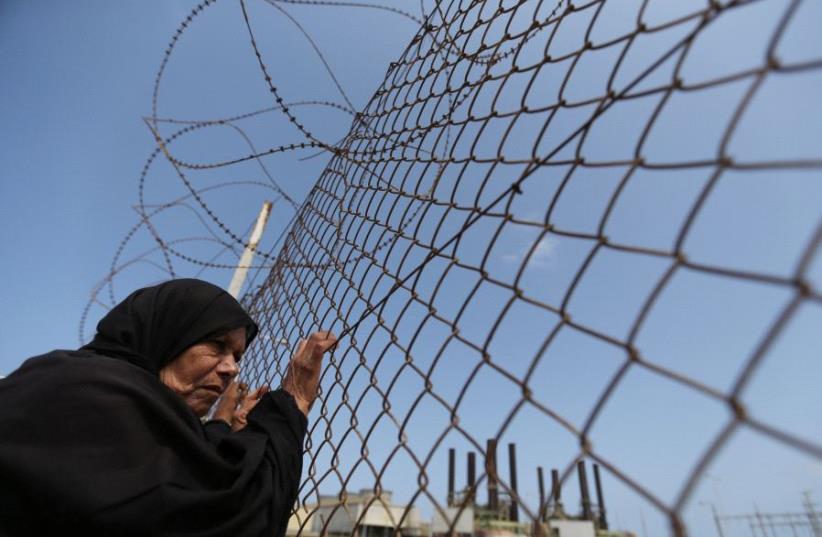 A Palestinian woman stands by a fence during a protest calling for an end to the power crisis, outside the power plant in the central Gaza Strip April 23, 2017. (photo credit: REUTERS)