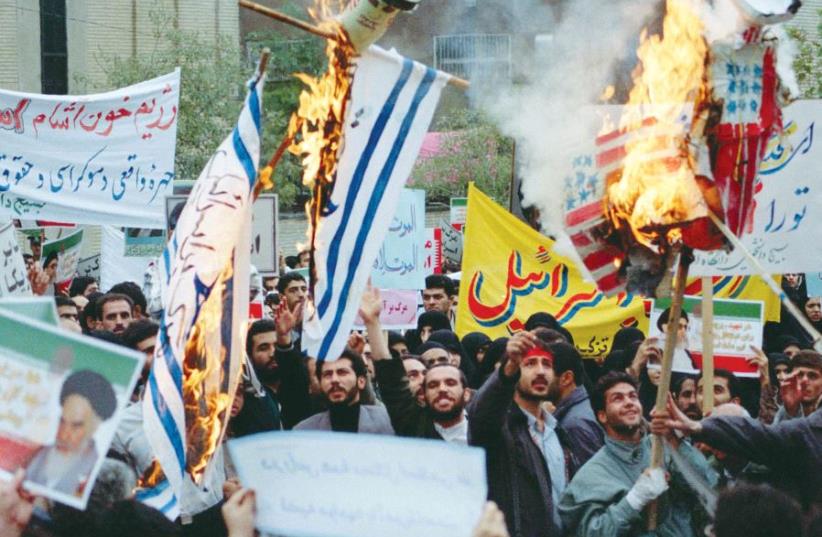 Iranian demonstrators hold placards and burn Israeli and US flags at a demonstration in Tehran in October 2000 – but this wasn’t always the prevailing Iranian approach (photo credit: REUTERS)