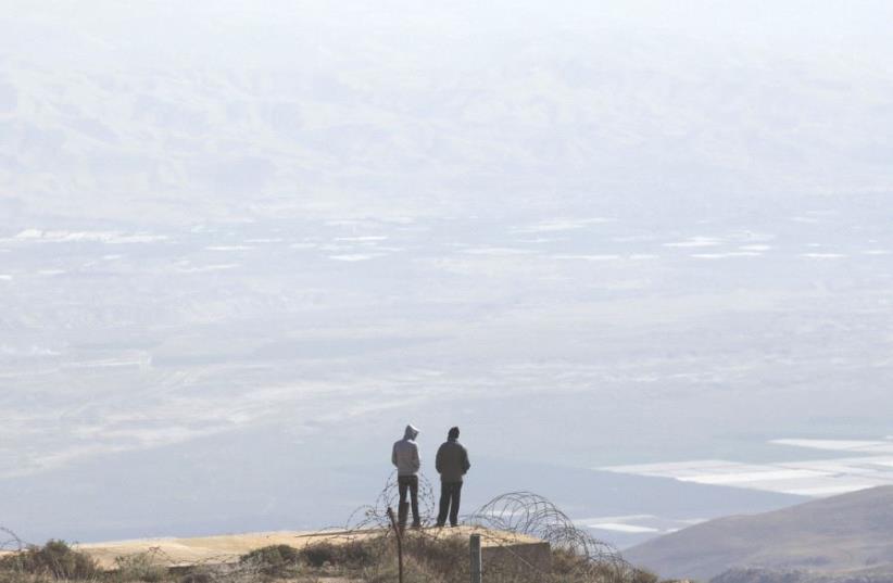 TWO SETTLERS stand atop a ridge in the West Bank. (photo credit: REUTERS)