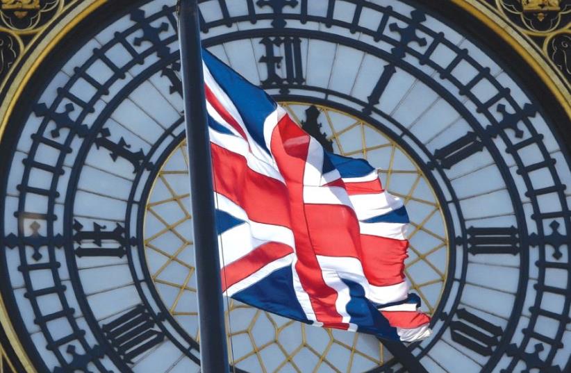 A Union Jack flag flies in front of the clock face on the Houses of Parliament in central London (photo credit: REUTERS)