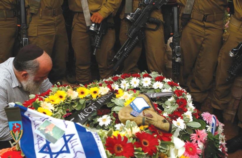 SOLDIERS STAND next to the grave of their comrade Lieutenant Hadar Goldin during his funeral in Kfar Saba in August 2014 (photo credit: REUTERS)