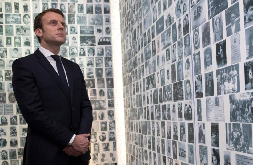Emmanuel Macron, candidate for the 2017 presidential election, looks at some of the 2,500 photographs of young Jews deported from France during WWII, as he visits the Shoah Memorial in Paris, France, April 30, 2017 (photo credit: REUTERS)