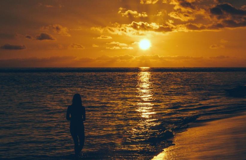 Young woman watching the sunset at the beach (illustrative) (photo credit: ING IMAGE/ASAP)