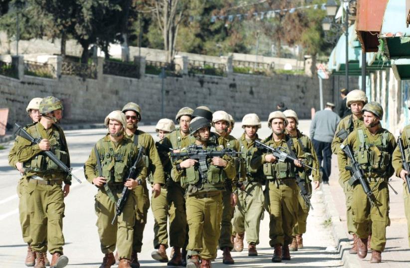 IDF soldiers patrol after clashes with Hebron Jews seeking to thwart evacuation from the city’s wholesale market in 2006 (photo credit: AVI OHAYON - GPO)