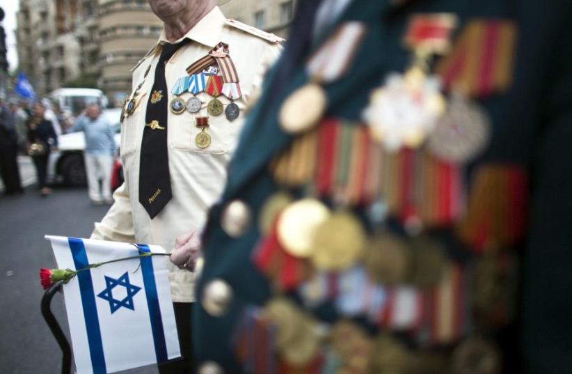 A World War Two veteran holds a flower and Israel's national flag during a march in Jerusalem commemorating the 70th anniversary of VE (Victory in Europe) Day May 10, 2015 (photo credit: REUTERS)
